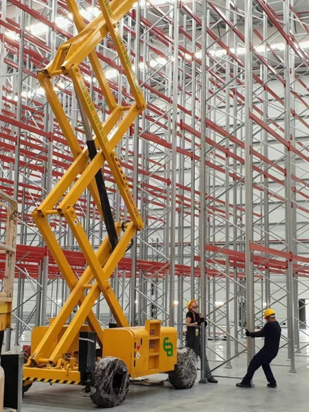 Dos montadores colocando un bastidor junto a una plataforma de tijera