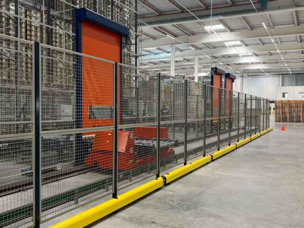 Bordillo de protección junto a las puertas rápidas naranjas del almacén automático